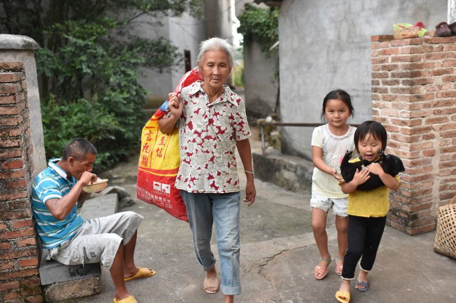 Huang Huiying has to get the meals ready for her mentally-retarded sons before leaving home to send her granddaughter to school and later collect scraps at local construction sites. In the picture, her second son eats when Huang arrives home with her two granddaughters. [Photo/Sina] 