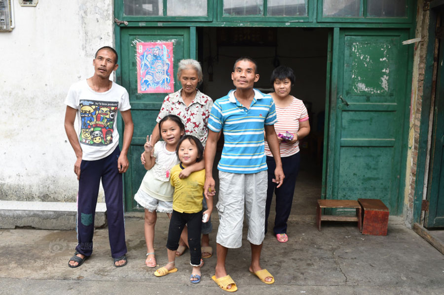 Huang Huiying and her three mentally-retarded children and two healthy grandchildren pose for a picture. Huang always worries that nobody will take care of her children and grandchildren after she dies. [Photo/Sina]