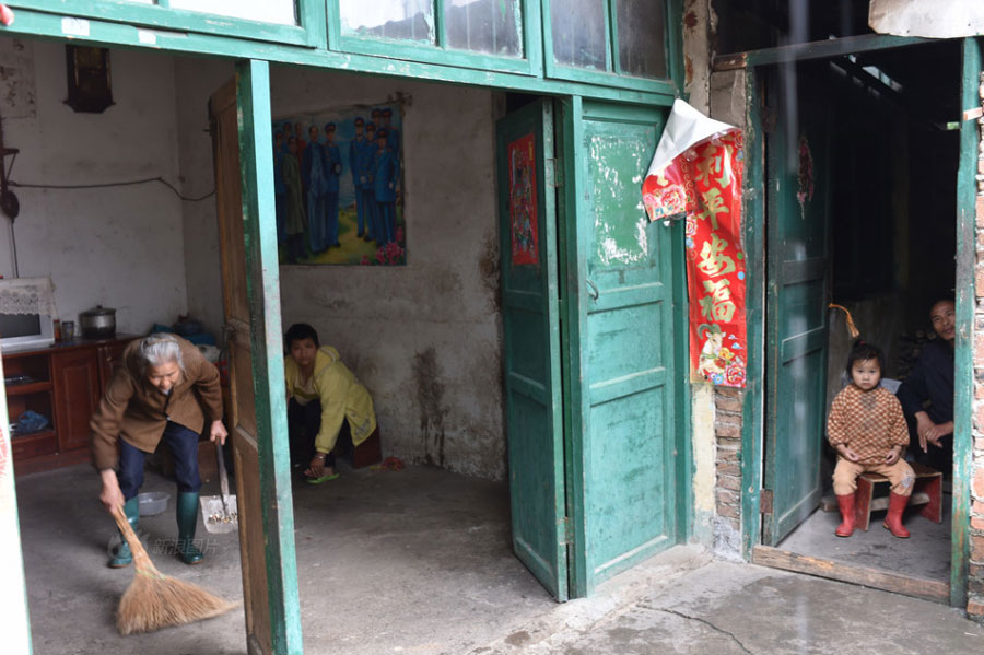 Huang Huiying, 66, lives in Shatang Village, Lingui County in southern China&apos;s Guangxi Zhuang Autonomous Region. During the long years, Huang has endured all kinds of hardships, struggling to bring up her three mentally-retarded children and two healthy grandchildren. In the picture, Huang does housework while her children and granddaughter watch. [Photo/Sina]