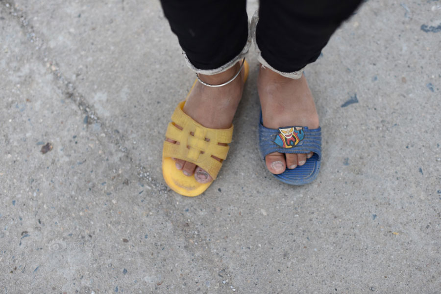 Huang Huiying&apos;s second granddaughter wears slippers of different size and color which Huang picked up in a garbage heap. [Photo/Sina] 