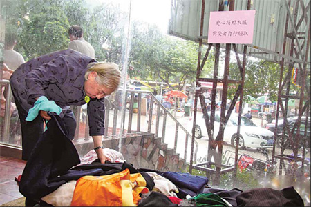 An elderly woman looks through a pile of donated clothes at a temporary storm relief shelter in Nanping, a city in northern Fujian province hit by heavy rainfall last month. Many people donated cash and clothing for the victims.