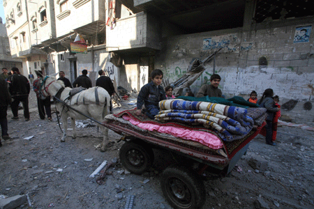 Palestinians take their belongings out of the rubble of a destroyed building following the Israeli military operations in Gaza City on January 14, 2009. Israeli aircrafts pounded Palestinian militants' rocket-launching pads, weapons arsenals and dozens of arms smuggling tunnels near the Gaza-Egypt border, according to the military source on Wednesday, as UN Secretary-General Ban Ki-moon headed to the region to help ease the tension in the Palestinian territory of Gaza Strip.[Xinhua]