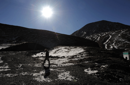 A foreign tourist walks along the Karola glacier, which situates at the boundary between the Nagarze county and the Gyangze county of southwest China's Tibet Autonomous Region, on January 14, 2009. The glacier tongue locates at an altitude of 5,560 meters, extending from the top to the roadside.