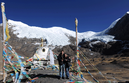 Two foreign tourists take pictures in front of the Karola glacier, which situates at the boundary between the Nagarze county and the Gyangze county of southwest China's Tibet Autonomous Region, on January 14, 2009.