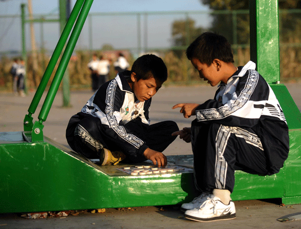 Two boy students enjoy playing chess during the break time. 
