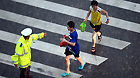 A traffic policeman directs children to cross the road in torrential rain in Jinan, capital of east China's Shandong Province, July 29, 2013.