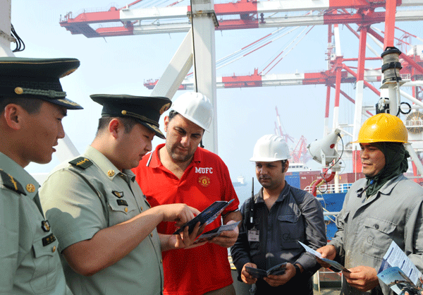 Officers from a border check station’s legal aid service department talk to sailors on board an Italian vessel about China’s entry and exit laws. The Bayuquan border check station is the first of its kind in Liaoning province to establish the legal aid service in order to ease conflicts. [Photo/Xinhua]