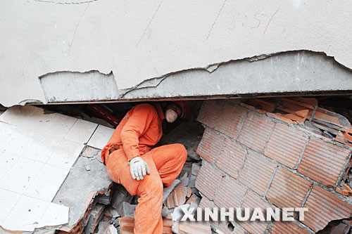 5月18日，一名消防干警在北川县城的废墟中搜救。当日，在汶川地震重灾区北川，解放军、武警官兵和预备役救援人员一起冒着危险，继续在废墟里搜救并进行清理工作。