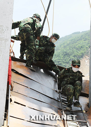 　5月18日，解放军某部的救援队员在通过北川县城内的一座危桥。当日，在汶川地震重灾区北川，解放军、武警官兵和预备役救援人员一起冒着危险，继续在废墟里搜救并进行清理工作。