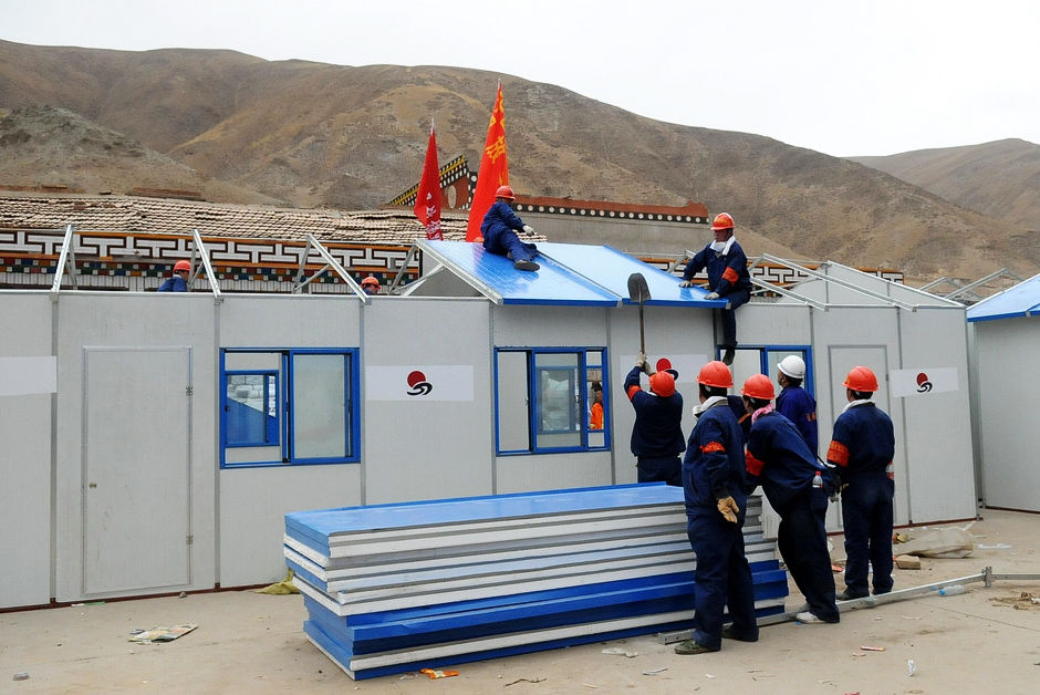 4月17日，工人们在青海省玉树藏族自治州孤儿学校操场上搭建板房教室，为18日学校的复学做准备。