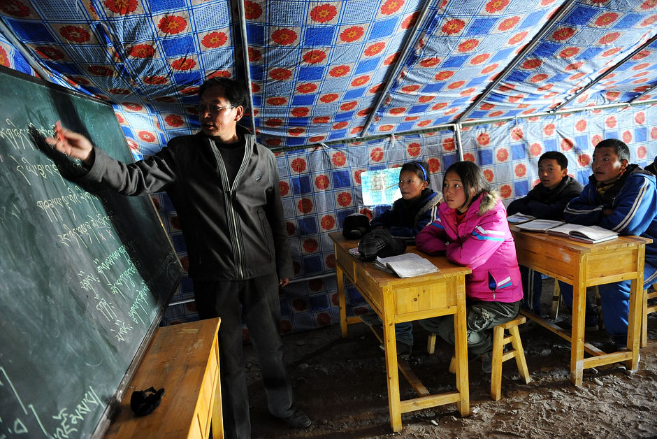 4月18日，玉树藏族自治州第一民族中学八年级老师次成尼玛（左一）在帐篷教室内给学生上课。