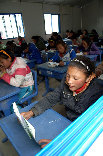 4月17日，青海省玉树藏族自治州孤儿学校四年级学生拉毛（前右）在板房教室内上课。 