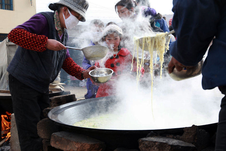 4月18日，青海省玉树州，晚饭时间，孩子们在锅灶前排队打饭。