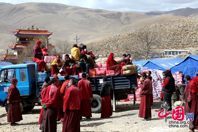 19日是玉树地震第5天，全国各地救灾、救援、捐献物资的队伍源源不断陆续开进灾区。当前，玉树灾区当务之急是继续寻找生存者，救治外运伤病员，解决群众衣食住问题，即灾区群众要有饭吃，有帐篷住，有饮用水喝。这是僧人们在向周边农牧区群众运送食品。 成为东/摄影