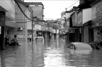 6月15日，开化县华埠镇被水淹没的街道，几位受困群众正在等待转移。新华社发