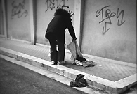 一位老妇人在捡拾散落在街边人们丢弃的衣服。
