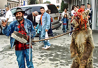 在城市庆祝活动上，吉普赛老人牵着一只熊跳舞乞讨。