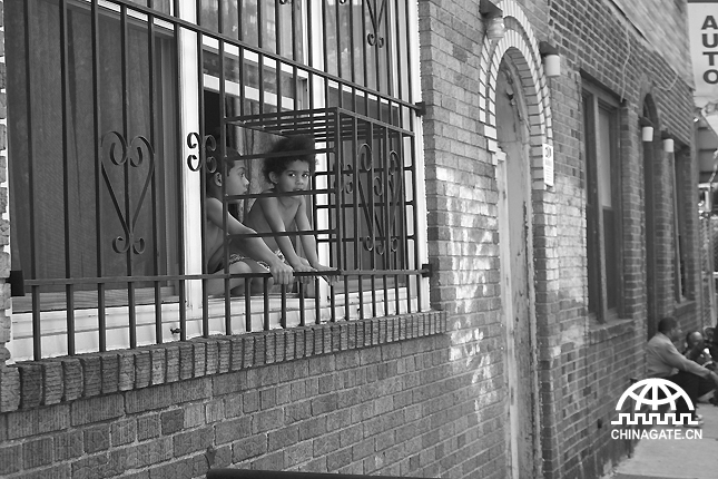 两个无人照看的小孩坐在窗边，看上去像是被关在笼子里的小动物。