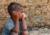 村庄里的一个小男孩握着一包摄影师给他的饼干，像是在沉思的样子。