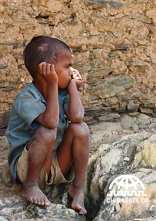 村庄里的一个小男孩握着一包摄影师给他的饼干，像是在沉思的样子。