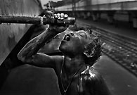 由于贫困，人们喝不上干净的水。Khaled，这个十三岁的少年，正在火车边上接一根管子里水喝。这根从火车车顶延伸下来的水管专门为车厢提供饮用水。