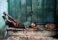 街边一家没有营业的商店前的石阶上，一个流浪小孩和一条流浪狗各占一边，躺在那里午休。印度的流浪儿童在全世界数量最多，仅加尔各答，大约就有超过12万5千流浪儿童。