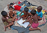 流浪儿童对书产生了兴趣，正聚在一起看书。印度政府正在采取措施，向所有的贫困儿童提供义务教育。