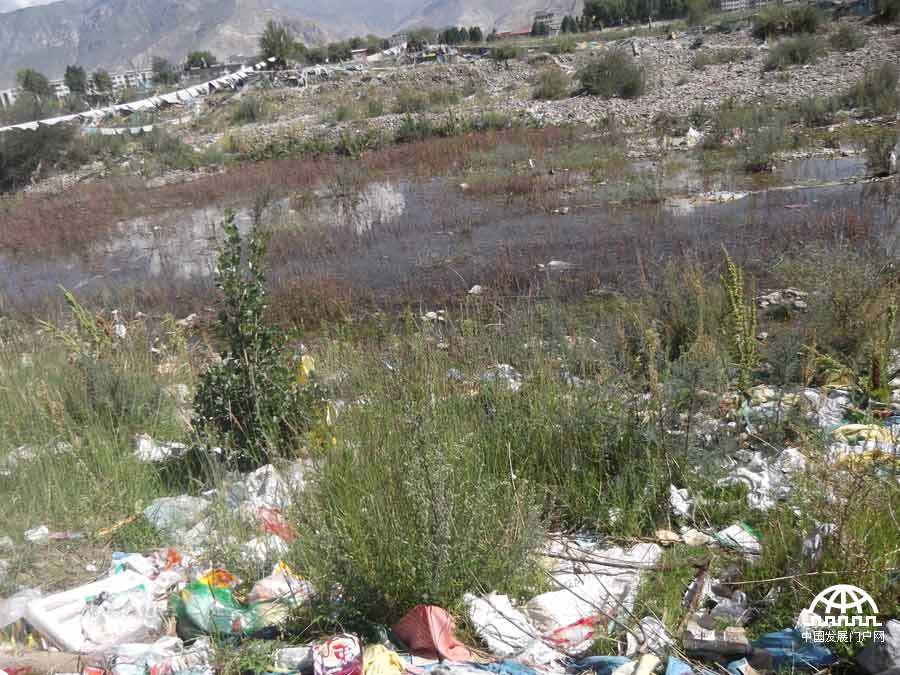 拍摄者：强巴嘉措 原本以为经幡的后面是一条美丽的河流，未曾想眼前的场景是如此的脏乱不堪，我十分的心痛。所以我拍下来想让更多的人知道，呼吁大家好好爱护环境，爱护我们美丽可爱的家乡，并且希望大家能够做到表里如一，在城市能看到的地方以及不能看到的角落都能做到干干净净的。