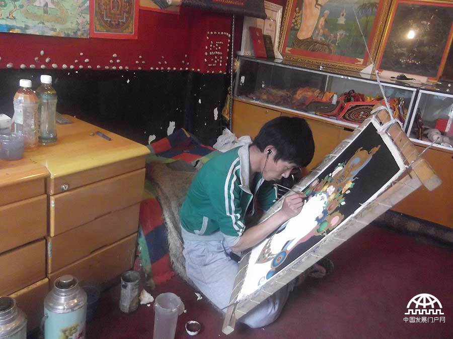 拍摄者：边巴顿珠 那天下午我和贡布哥行走在八角街旁的小巷里，当我们走进一家小店时，贡布哥让我不要出声。我马上意识到这是一间唐卡店，因为我的哥哥就是一名唐卡师。唐卡是藏民族特有的文化艺术品，而唐卡师很好地传承了民族的优秀文化，我对他们充满了敬仰之情。