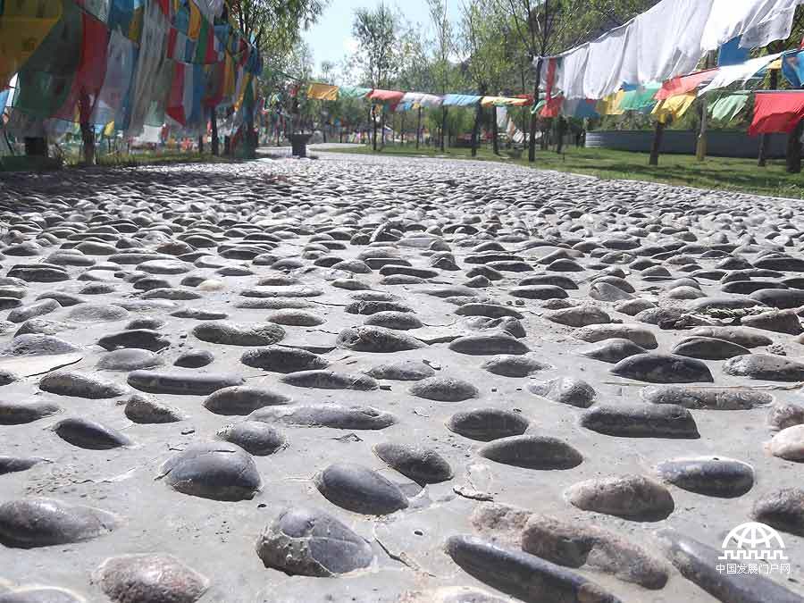 拍摄者：贡嘎顿珠 在我心里盲道是凸起的石头和其他的路不同，让我知道前面的路非常安全。这条盲道上镶嵌的石头与其他盲道上的石头不同，它是光滑的鹅卵石，走在路上好似有人在帮我足底按摩一样十分舒服。