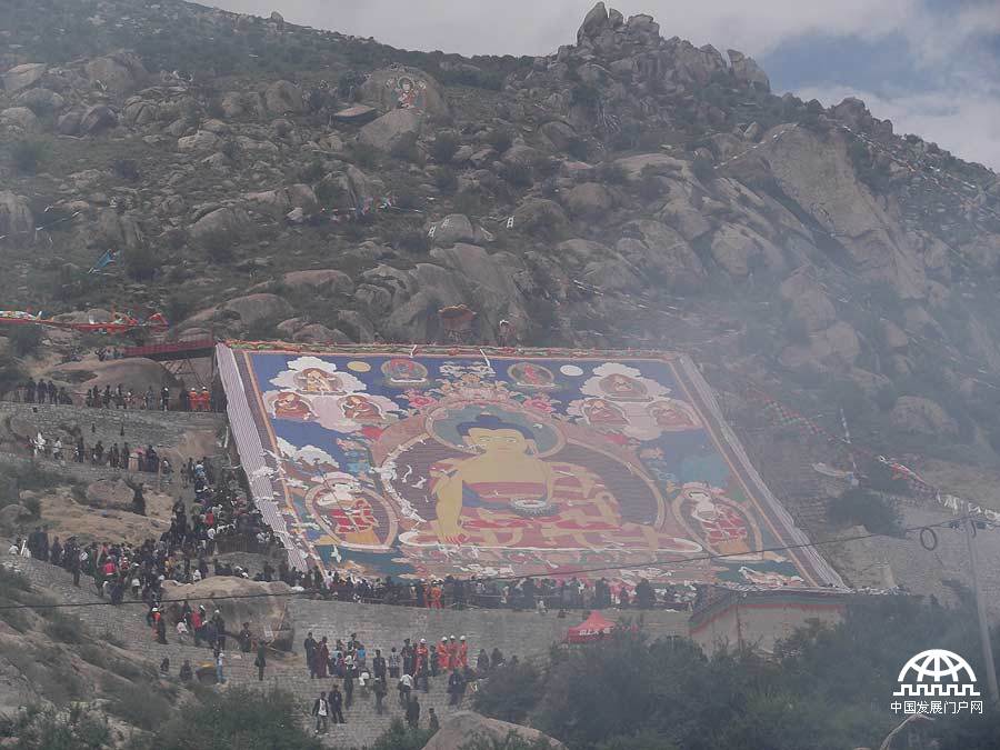 拍摄者：贡嘎顿珠 2012年8月17号是拉萨盛大的节日 — 雪顿节，是具有悠久历史的拉萨独特的节日。这是我第一次去哲蚌寺观看展佛，我发现不管有多辛苦，多喘，大家都非常卖力的往上爬。当这副唐卡出现时，周围的人都发出赞叹的声音，朋友向我描述了唐卡的样子，我也很想记录下这庄严的一刻。