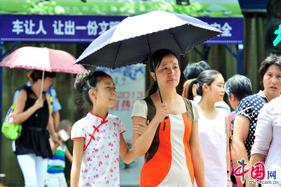 2013年7月30日，湖北宜昌市民在骄阳下通过夷陵区交通十字路口。中国网图片库 张国荣摄影