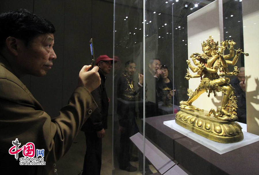 2013年11月6日，观众在“金色中国”展上用手机拍摄清代铜鎏金上乐金刚双身立像。