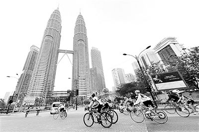 1月5日，在马来西亚首都吉隆坡，人们骑自行车经过双子塔。