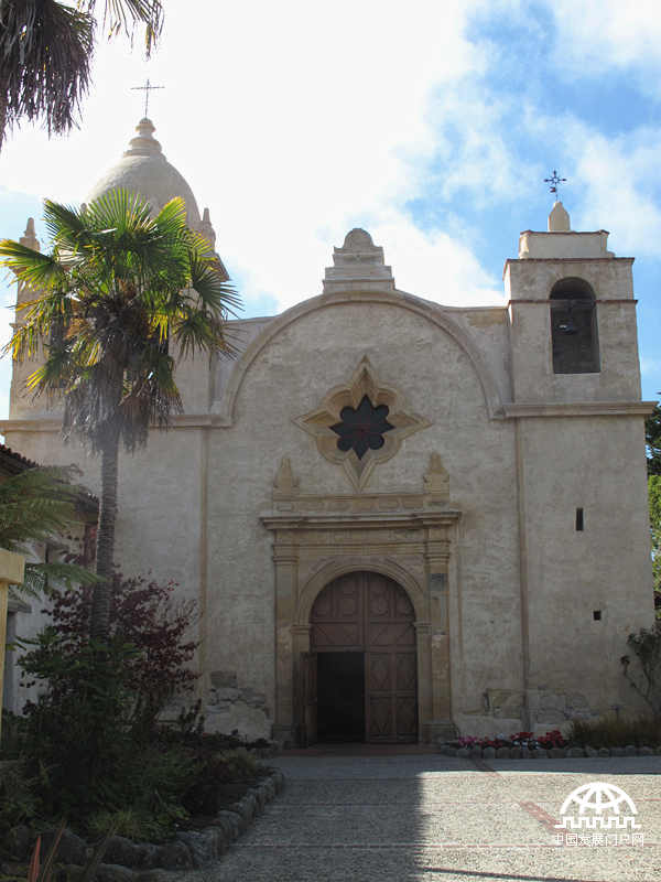 始建于1771年的卡梅尔教堂，全名是Mission San Carlos Borromeo del Rio Carmelo。泥砖风格的外墙古朴雅致，与加州的蓝天、棕榈树相映成趣。（中国发展门户网 焦梦 摄）