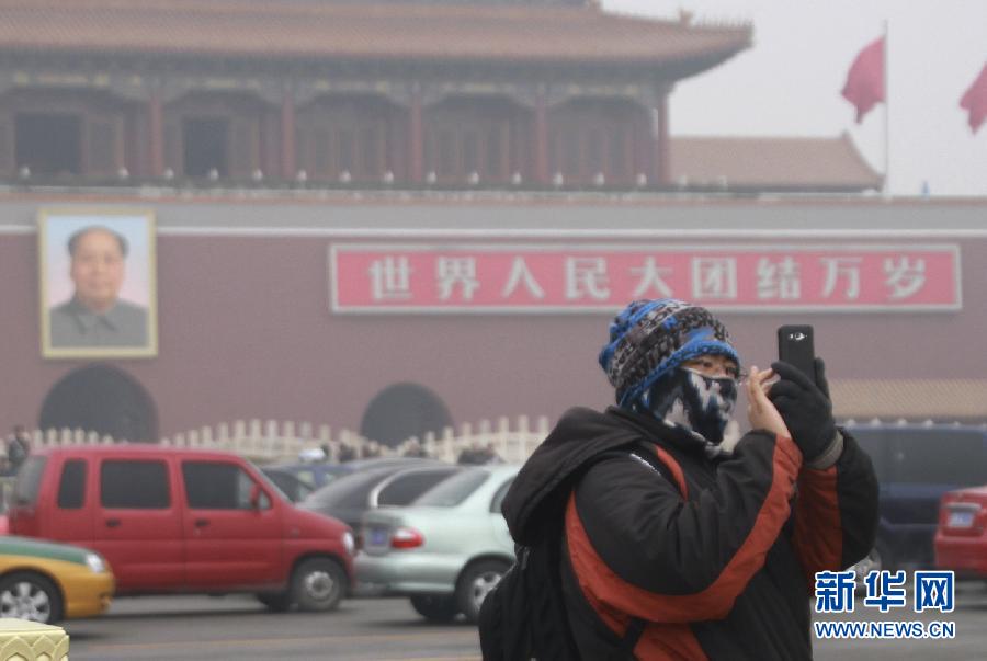 2月20日，一名戴着口罩的游客在天安门广场拍照。新华社发（何光 摄）