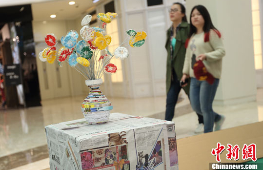 图为4月28日晚，市民被废旧报纸制成的花瓶花束吸引。南京“旧物智造”主题展倡导环保生活