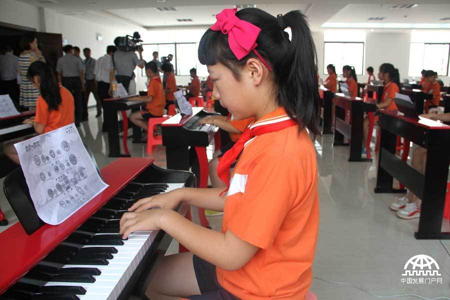 2014年6月7日，由中华少年儿童慈善救助基金会发起建设的共青儿童村正式建成启用，小学生进行电子钢琴表演。中国网/中国发展门户网魏博 摄