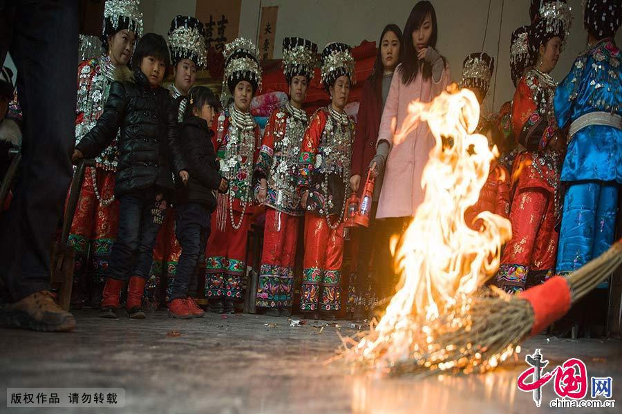  新娘龍玉婷的伯父點燃了火把，象征新人今后的生活紅紅火火，再親手交給新郎的堂兄。按鳳凰苗家習俗，新郎官不去迎親，新人由老兄接回。中國網圖片庫 尹忠/攝 