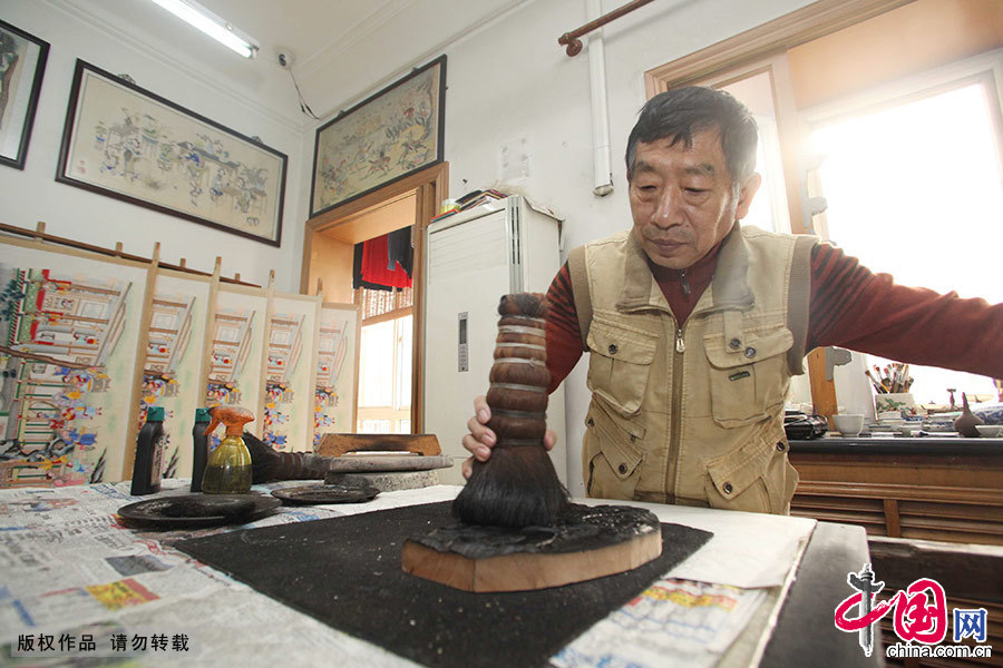  出生年画世家的霍庆有从小耳濡目染，至今按照祖辈的要求，严格执行制作的每一道工序。先用木板刻，再用墨印刷，等上一个半月油墨彻底干了，才用精心调好的水彩填色。图为霍庆有展示年画制作流程。中国网图片库 旨阅/摄