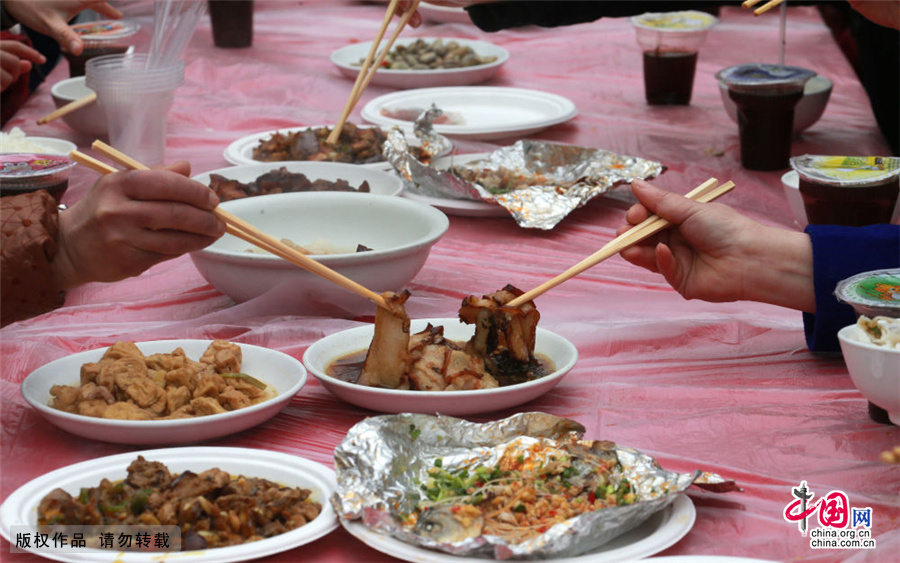 2月7日，贵州安顺好吃一条街开业，两位食客在夹盐菜肉。中国网图片库 卢维/摄