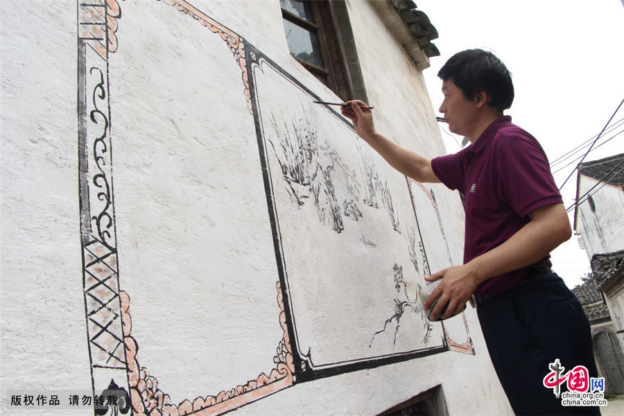  徽州彩绘壁画非遗传承人、安徽省黄山市马头墙书画院副院长吴叶生在白墙上描绘山水主题的徽州彩绘壁画。中国网图片库 吴孙民/摄