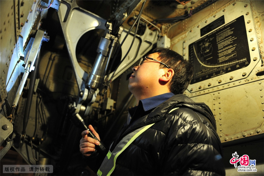 2015年2月10日晚，單志鵬按照工作單，對飛機前起落架艙逐項檢查，確保各部件運轉良好。中國網圖片庫 王偉/攝