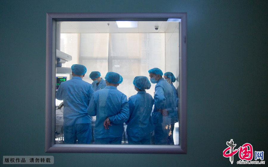 2015年2月7日，郑州，透过窗口，能看到医生们早上查房的身影。时间对于患者家属来说走的很慢，因为每一分等待都充满焦灼；对于医护人员来说，时间却走的很快，因为抢救与护理，分分秒秒都是忙碌。在医患矛盾突出的今天，这一分焦灼与忙碌间，也许需要更多的是理解与换位。 图片来源：CFP