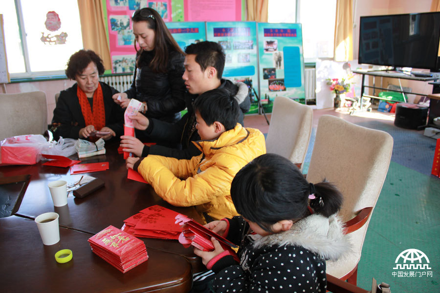 太阳村接待处，两个孩子正在帮工作人员装新年红包。中国网/中国发展门户网 魏博 拍摄