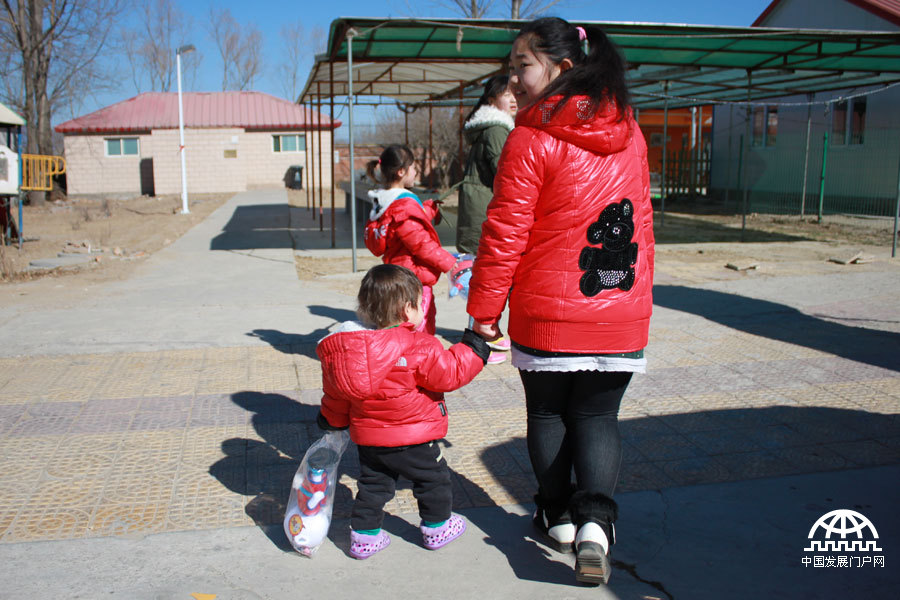  这是一个来自新疆的一岁多的小男孩，刚学会走路，在一个大孩子的带领下，拿着玩具开心地笑着。中国网/中国发展门户网 魏博 拍摄