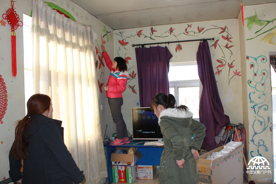  太阳村里，七八个女孩住在一个两居室的小套房里，两个卧室，一个客厅，暖气、卫生间、洗漱间齐全，一个女孩正在挂中国结。中国网/中国发展门户网 魏博/摄