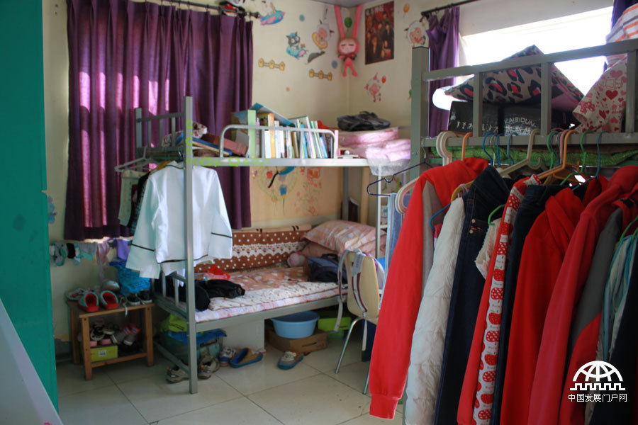  太阳村里，七八个女孩住在一个两居室的小套房里，两个卧室，一个客厅，暖气、卫生间、洗漱间齐全，一个女孩正在挂中国结。中国网/中国发展门户网 魏博/摄