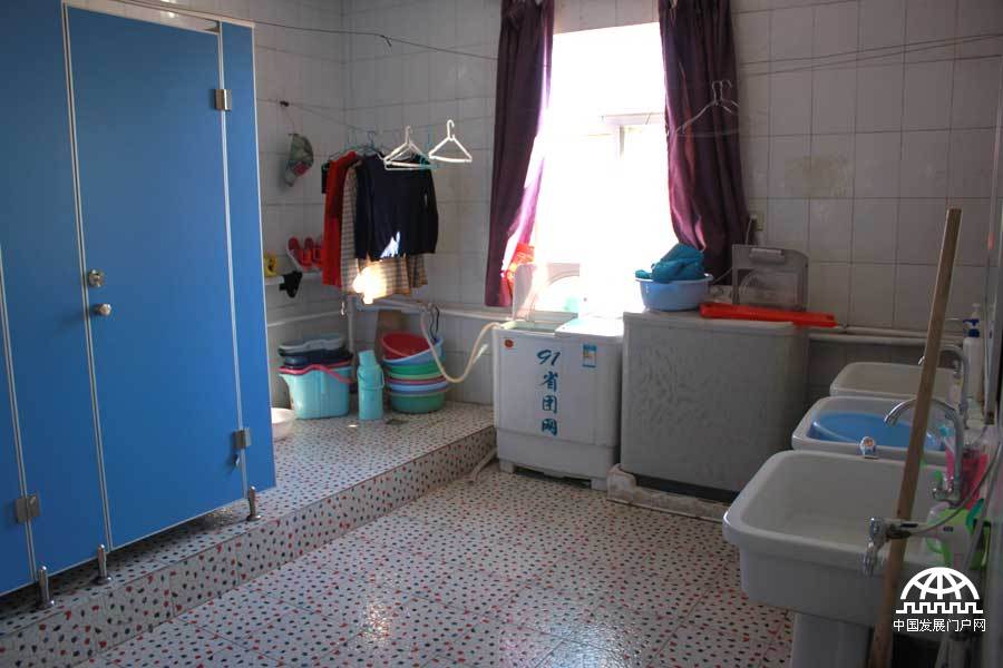  太阳村里，七八个女孩住在一个两居室的小套房里，两个卧室，一个客厅，暖气、卫生间、洗漱间齐全，一个女孩正在挂中国结。中国网/中国发展门户网 魏博/摄