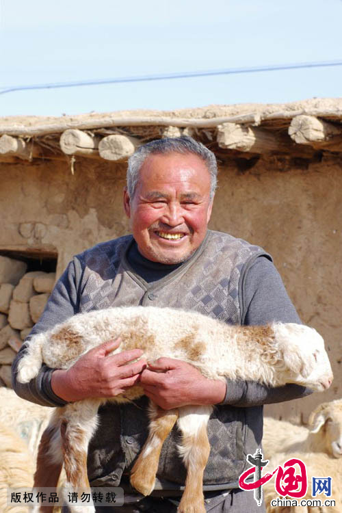  2015年3月9日，吕吉弟开心地抱住刚生下有1个月的羊羔。羊多了，家里的收入就多了，这让吕吉弟异常的开心。中国网图片库